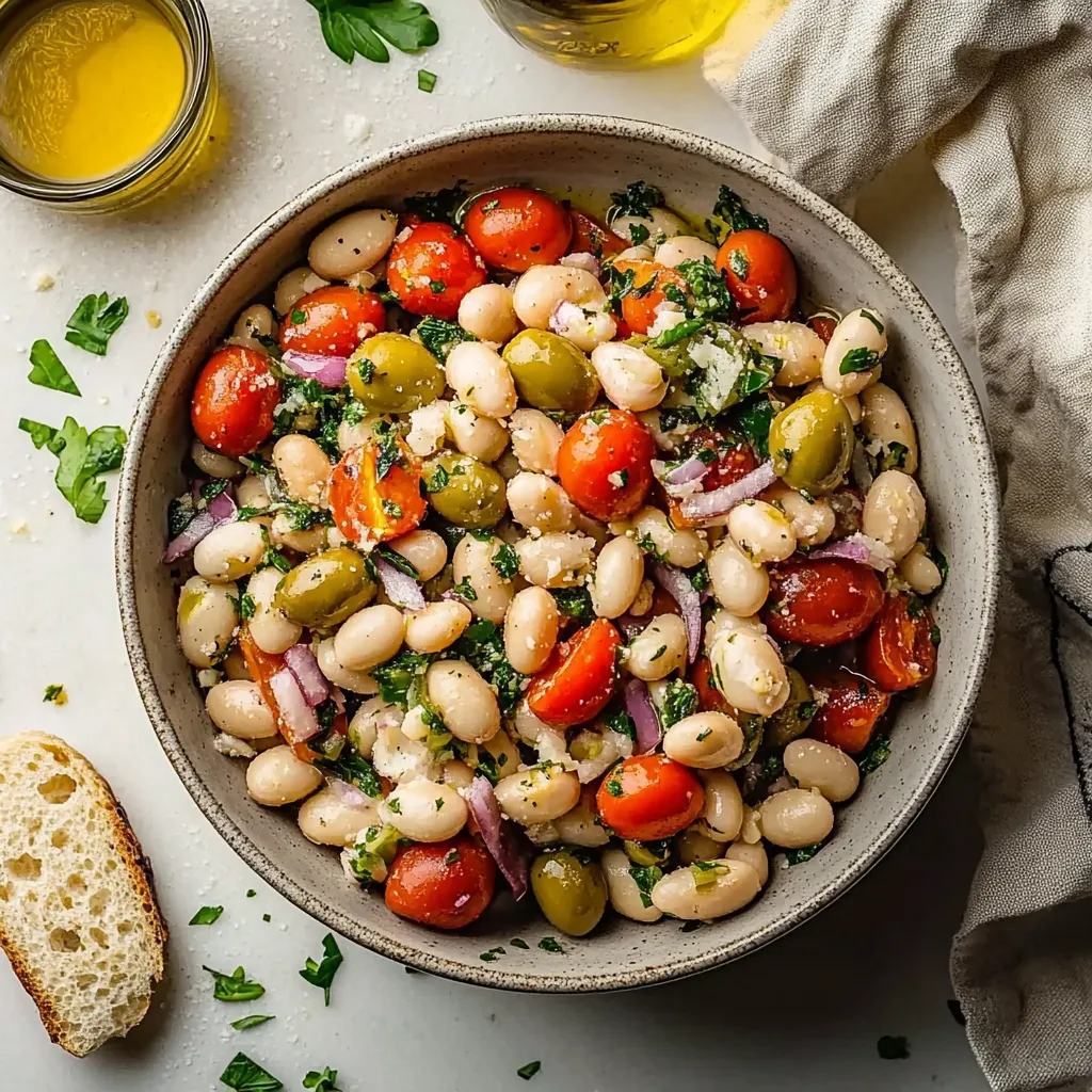 A bowl of food with tomatoes, beans, and olives.